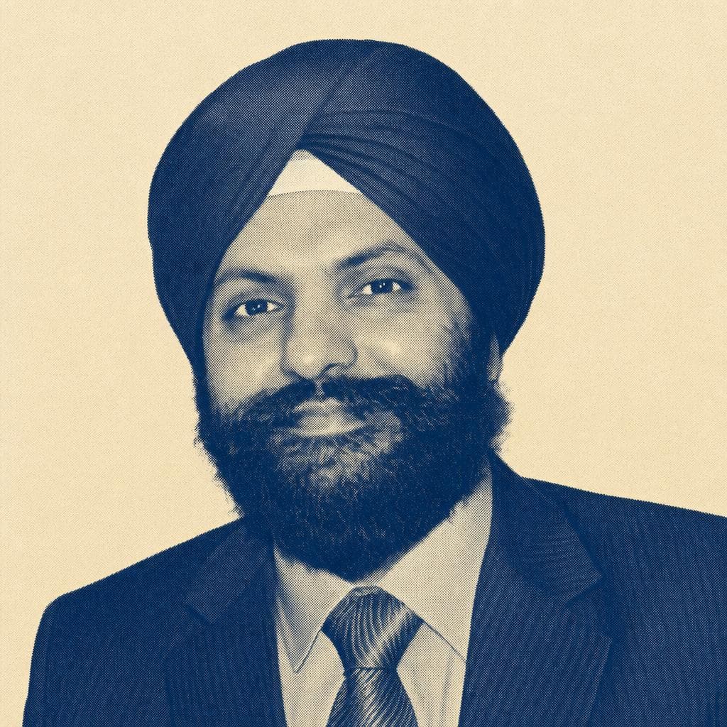 Inderpal Singh Chadha, in a black dastar, dark suit and patterned tie, photographed smiling.