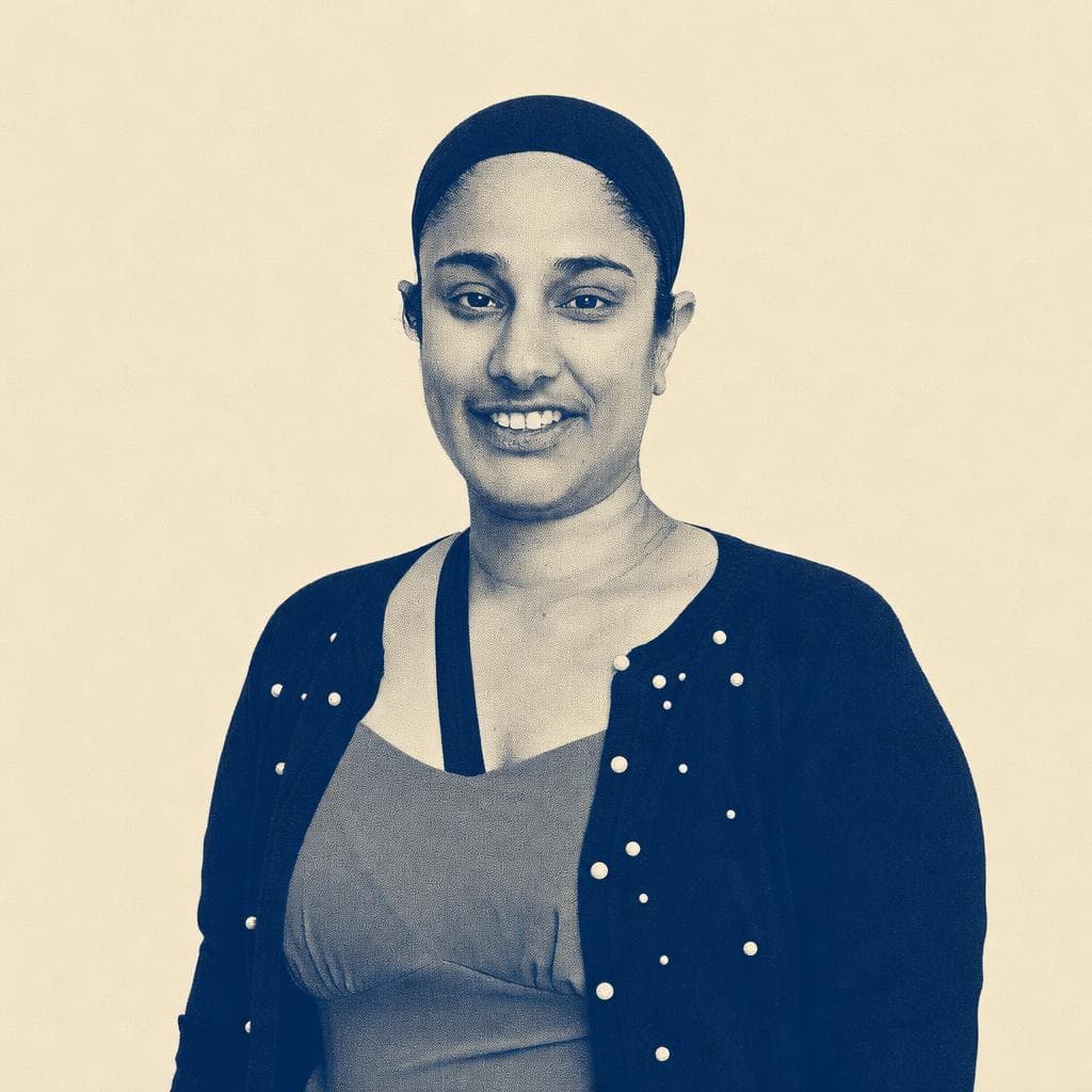 Jaspreet Bal, in a black head covering and a black cardigan with pearl detailing, photographed smiling.