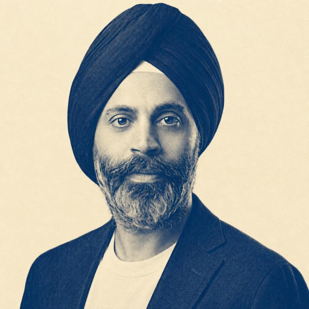 Karandeep Singh Anand, in a navy dastar and blazer, against a dark studio background.