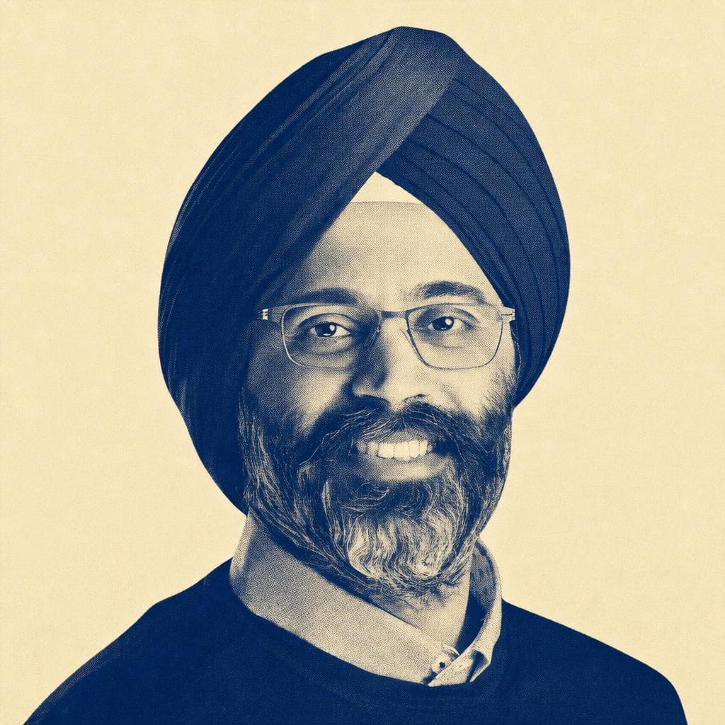 Karandeep Singh Anand, in a navy dastar and glasses, smiling warmly.