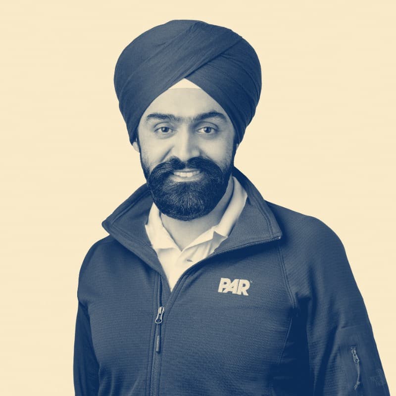 Savneet Singh, in a navy dastar and zip jacket, smiling.